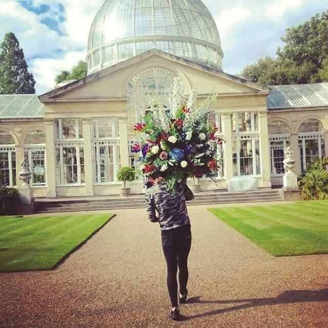 A Moyses Stevens florist carrying a tall floral arrangement at a historic London venue