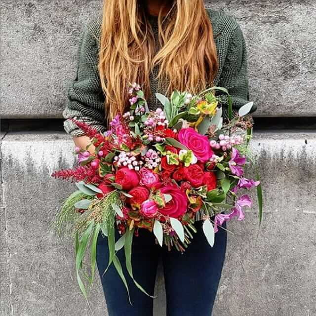A Moyses Stevens florist holding a large hand-tied bouquet of seasonal flowers