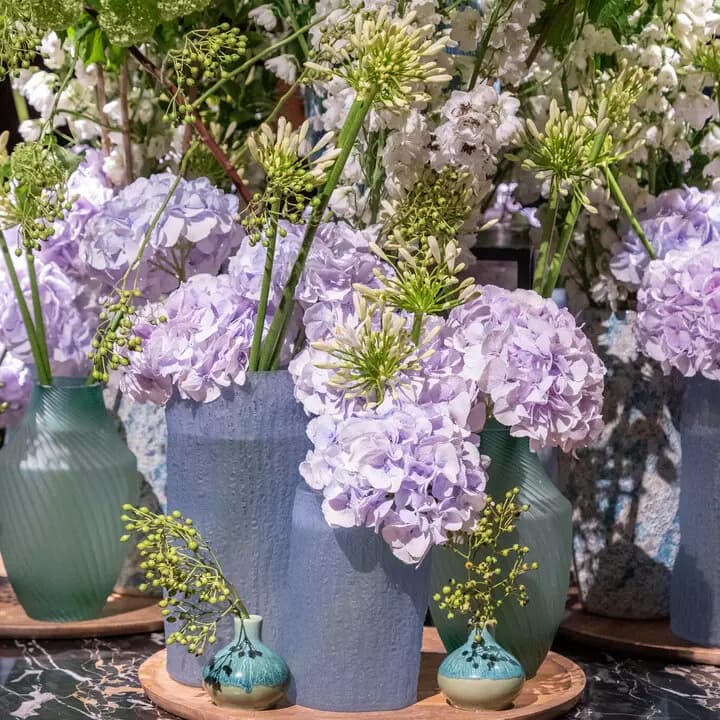Eco Glass pots in green hues holding seasonal flowers